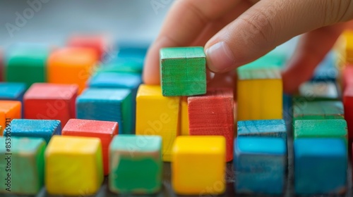 A hand arranging small building blocks into a structure, representing the construction of a new business foundation
