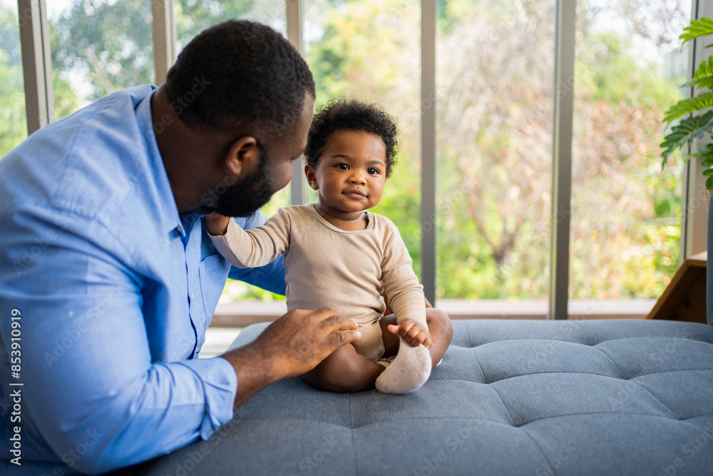 Portrait Of Happy African American Dad With Cute Little Baby Girl on couch at home in the living room, caring father smiling and amusing his girl while sitting on the couch, happy family Portrait Of Happy African American Dad With Cute Little Baby Girl on couch at home in the living room, caring father smiling and amusing his girl while sitting on the couch, happy family