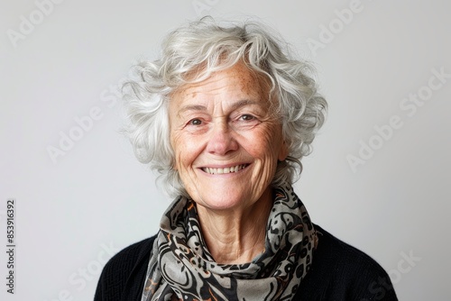 Portrait of a grinning woman in her 80s smiling at the camera while standing against white background © CogniLens
