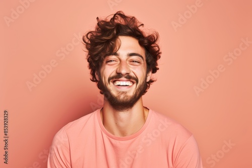 
Portrait photo of a cheerful Caucasian man, 26 years old, winking on a pastel salmon background