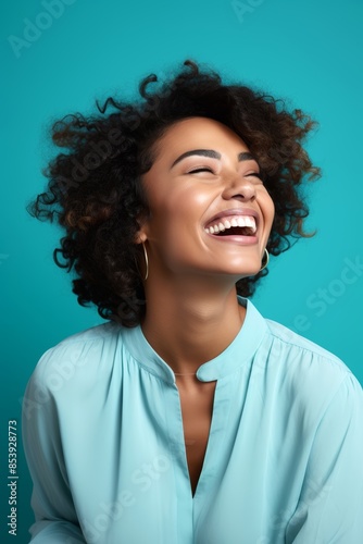 
Portrait photo of a joyful Afro-Caribbean woman, 29 years old, winking on a pastel cyan background