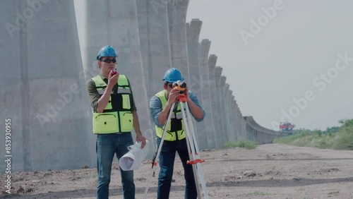 Surveyor with clipboard looking throughout digital level. Surveyors work  with digital level onsite construction.