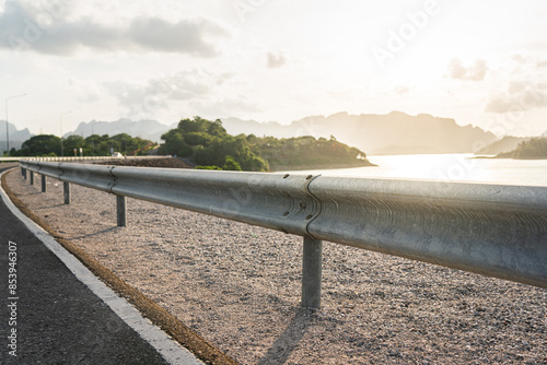 Roadside metal rail barrier structure which is installed on side of the road for protected the car accident. Transportation safety equipment object, selective focus. photo
