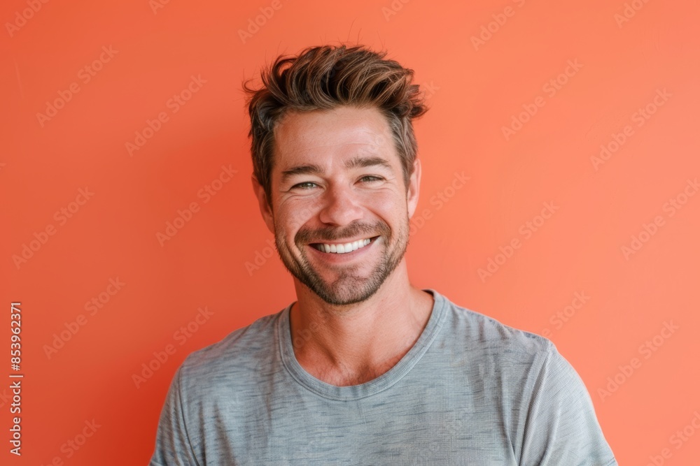 Portrait of a glad man in his 30s smiling at the camera isolated on pastel orange background Portrait of a glad man in his 30s smiling at the camera isolated on pastel orange background