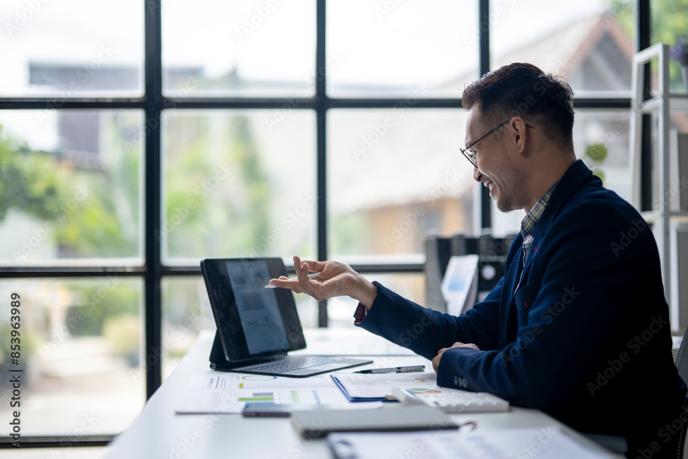 A man is sitting at a desk with a laptop and a tablet A man is sitting at a desk with a laptop and a tablet