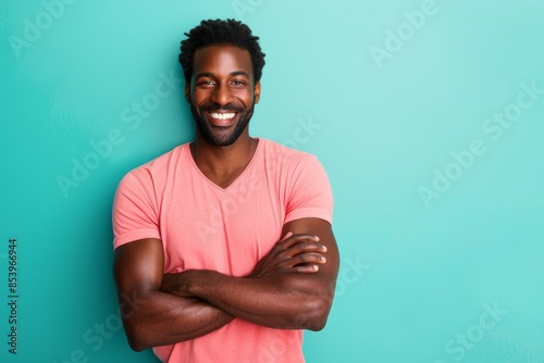 Portrait of a cheerful afro-american man in his 30s with arms crossed in front of pastel teal background photo