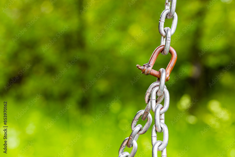 metal chain on a background of green foliage. fragment of an old metal chain. metal chain mount. reliable metal fastening metal chain on a background of green foliage. fragment of an old metal chain. metal chain mount. reliable metal fastening
