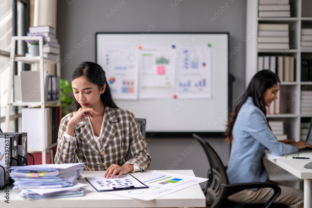 A woman is sitting at a desk with a white board behind her A woman is sitting at a desk with a white board behind her