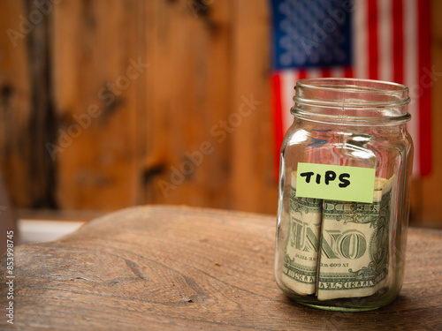 Tip jar with dollars and American flag background c