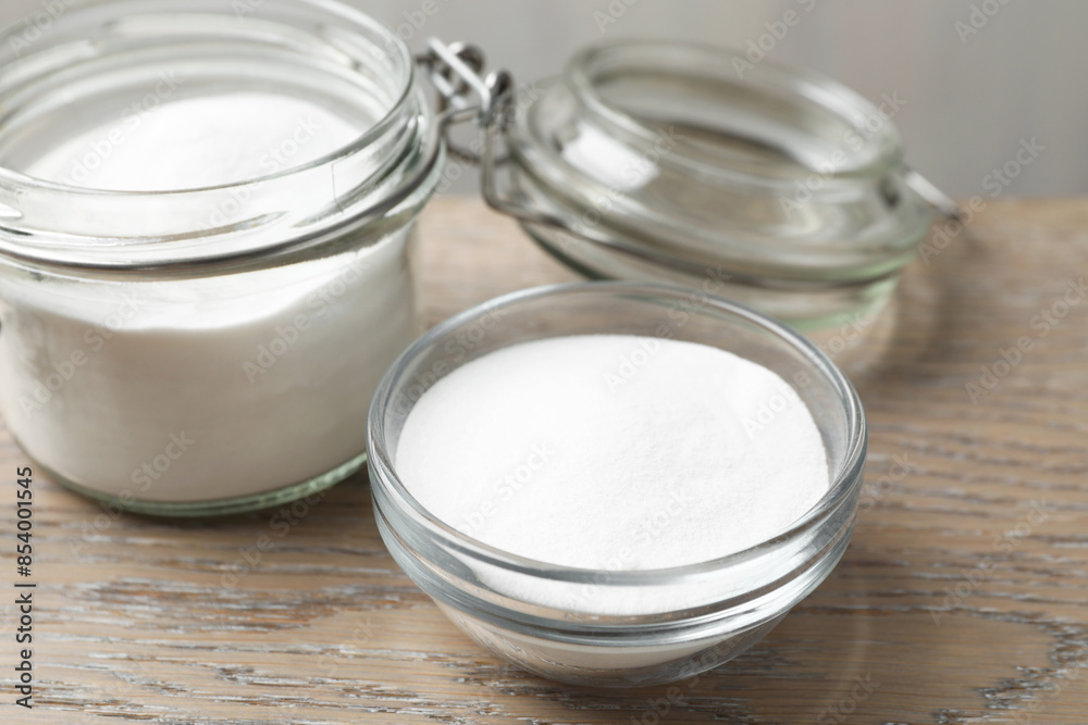 Baking soda in bowl and glass jar on wooden table, closeup Baking soda in bowl and glass jar on wooden table, closeup