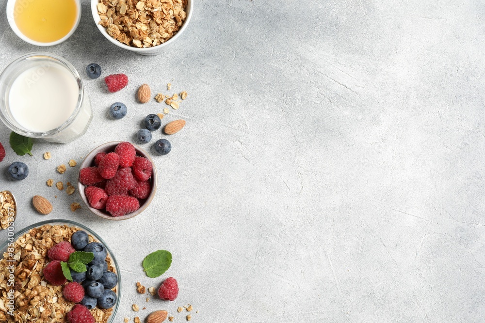 Tasty granola with berries, nuts and mint on grey table, flat lay. Space for text Tasty granola with berries, nuts and mint on grey table, flat lay. Space for text