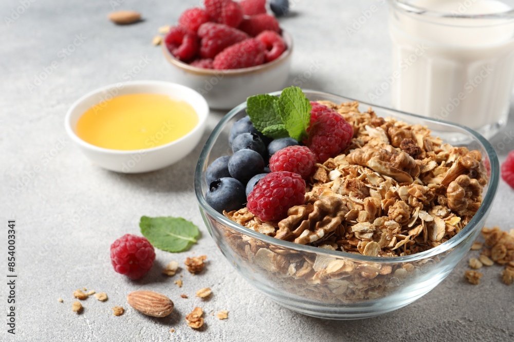 Tasty granola with berries, nuts and mint on grey table