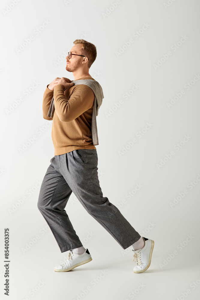 A stylish man wearing a brown sweater walks gracefully. A stylish man wearing a brown sweater walks gracefully.