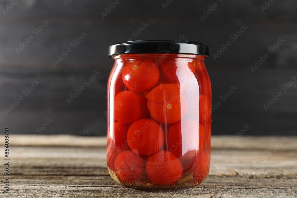 Tasty pickled tomatoes in jar on wooden table Tasty pickled tomatoes in jar on wooden table