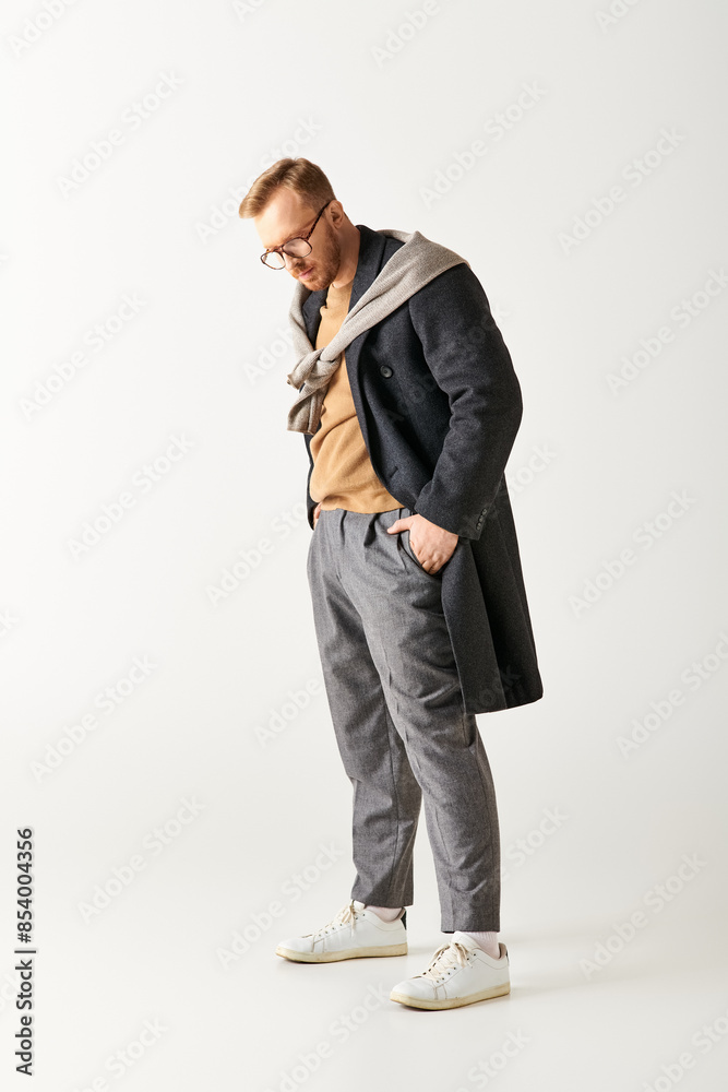 A man in glasses and a coat stands confidently.