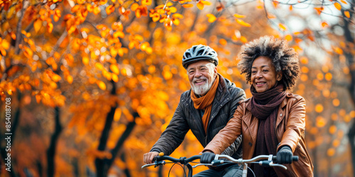 Senior couple on bikes. Happy people with bicycle in autumn park. Old people, man and woman with fall landscape background. Active cycle sport. Mature black couple exercises, healthy bike rides