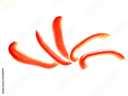 A close up of red peppers. The peppers are sliced and arranged in a row on white background. Food preparation concept. Nature colors. photo