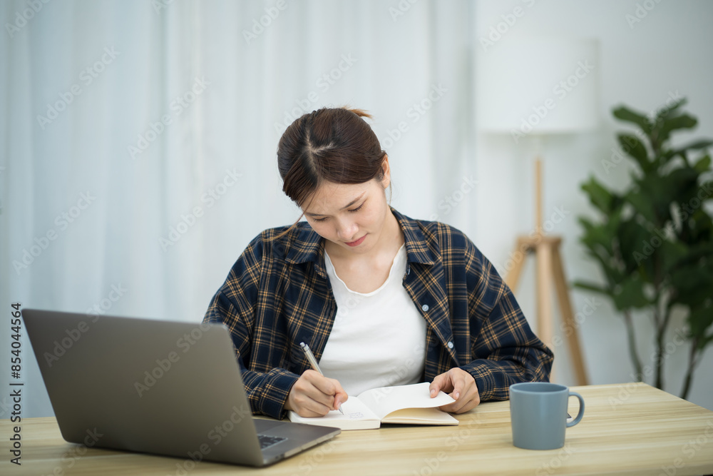 Happy beautiful Asian woman using computer laptop for work online at living room Happy beautiful Asian woman using computer laptop for work online at living room