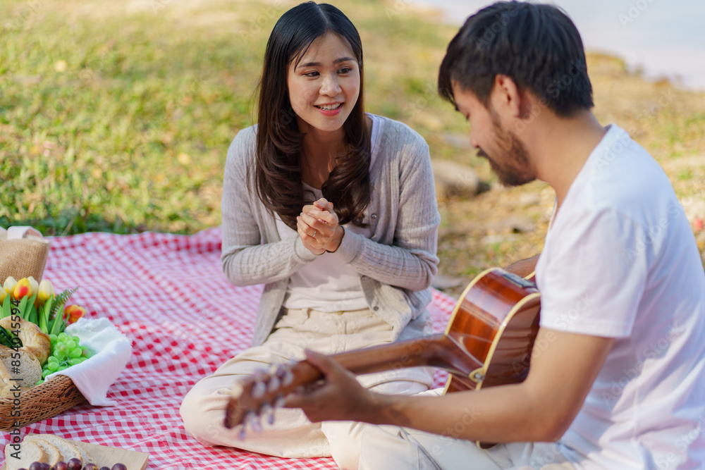 In love couple enjoying picnic time playing guitar in park outdoors Picnic. happy couple relaxing together with picnic Basket In love couple enjoying picnic time playing guitar in park outdoors Picnic. happy couple relaxing together with picnic Basket
