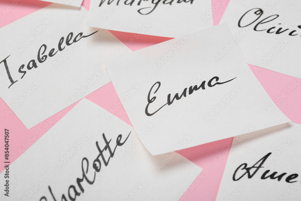 Paper stickers with different names on pink background, closeup. Choosing baby's name Paper stickers with different names on pink background, closeup. Choosing baby's name