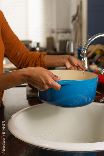 Close-up of a woman's hands filling a pot with water in the kitchen at home