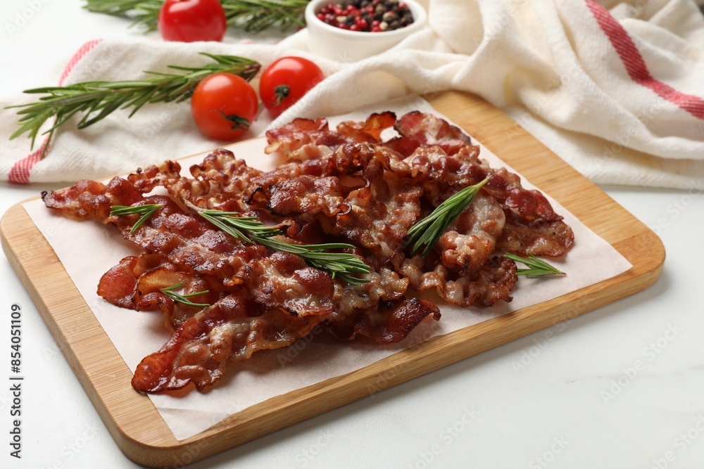 Slices of tasty fried bacon with rosemary on white table Slices of tasty fried bacon with rosemary on white table