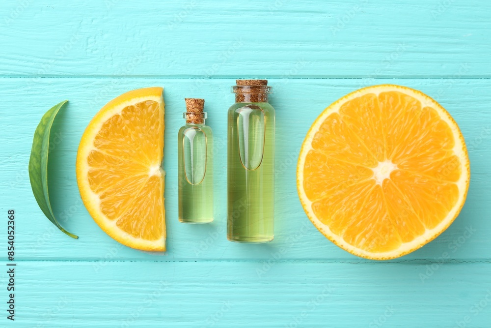 Bottles of essential oils, orange and green leaf on turquoise wooden table, flat lay Bottles of essential oils, orange and green leaf on turquoise wooden table, flat lay