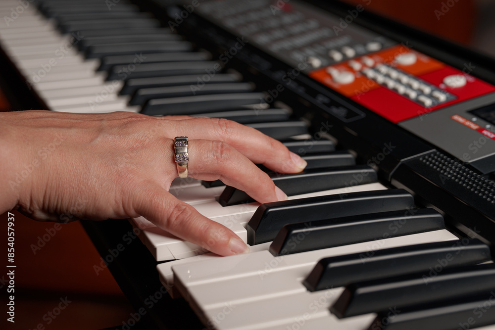 Fototapeta premium Female hand playing the electronic piano