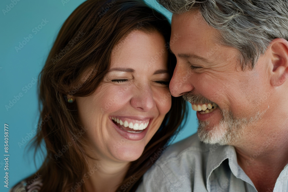 a Caucasian couple laughing together on a blue studio background a Caucasian couple laughing together on a blue studio background