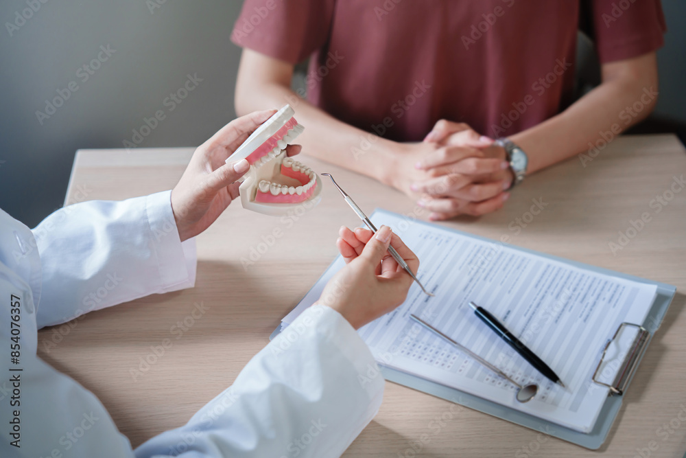dentist holding tooth model White healthy tooth Doctor doing dental treatment .