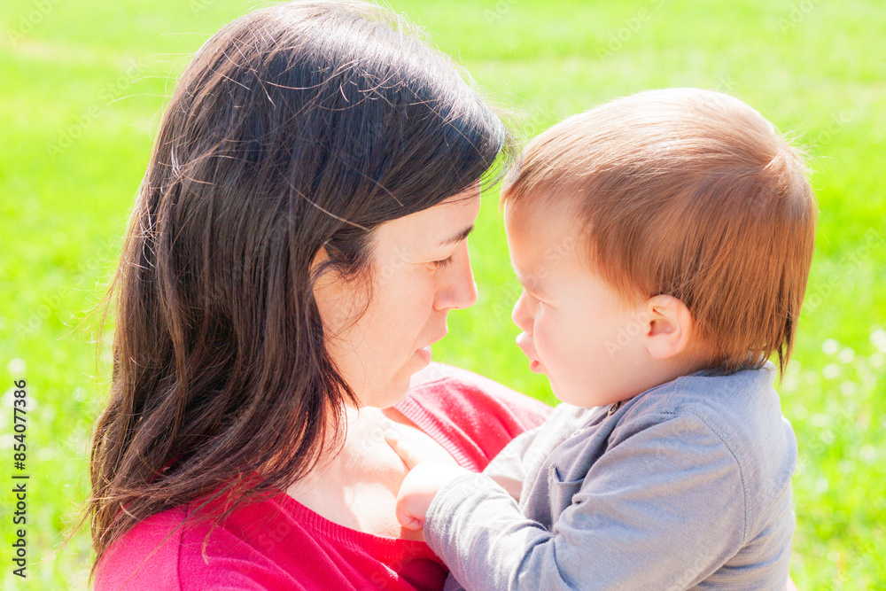 Tender glance between a mother and child beside a green meadow. Motherhood. Tender glance between a mother and child beside a green meadow. Motherhood.