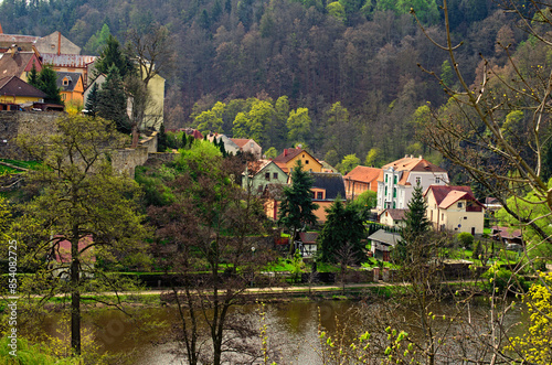 Picturesque aerial landscape view of Loket village. Colored residential houses on the slope of the mountain with ancient trees by summer sunny day. Bohemia, Sokolov, Karlovarsky Region,Czech Republic