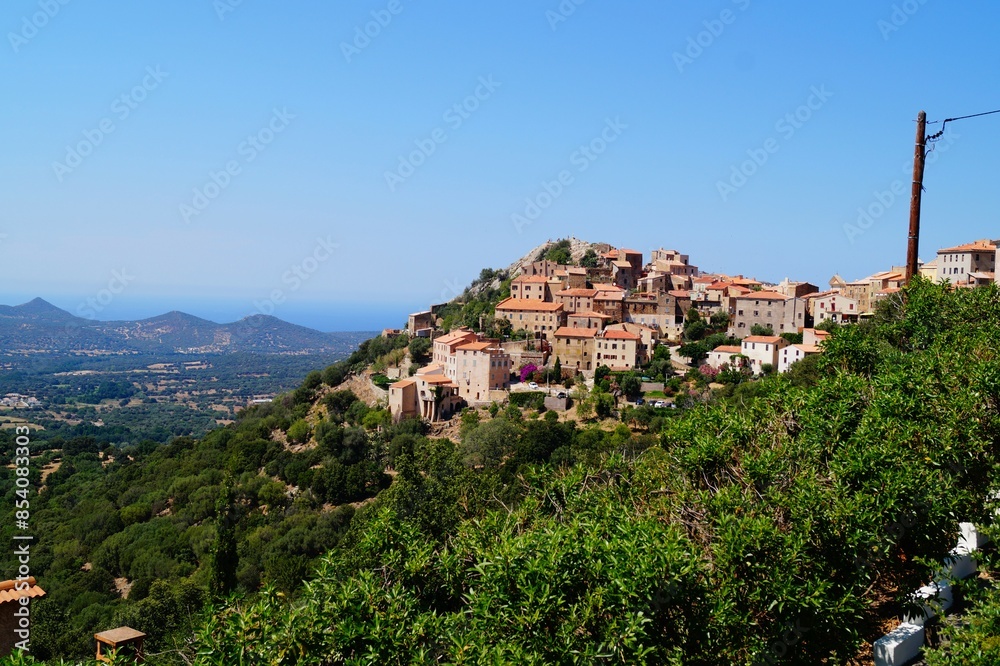 Obraz premium Picturesque views on the village Speloncato against the Mediterranean Sea, blue sky, green valley and mountains in sunny day. Balagne, Corsica, France.
