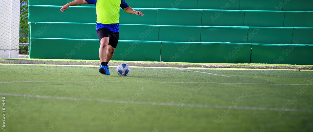Fototapeta premium Soccer players in action during a game on a grass field, focusing on their legs and the ball.