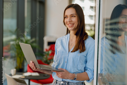 Free Download Woman smiles in a modern office with a laptop, creating a positive work environment - GFXLoad