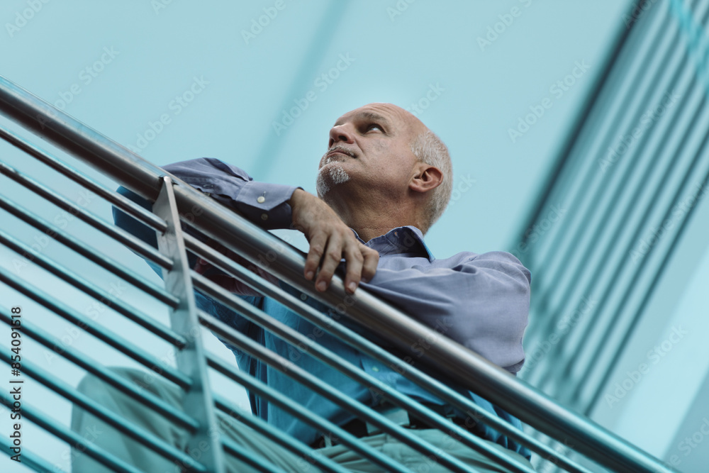 Senior businessman leaning on railing and contemplating future Senior businessman leaning on railing and contemplating future