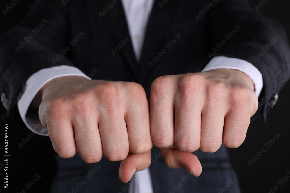 Obraz premium Businessman showing fists with space for tattoo on black background, closeup