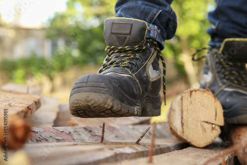 Photography Careless worker stepping on nail in wooden plank outdoors, closeup