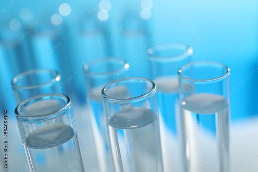 Many glass test tubes on light blue background, closeup Many glass test tubes on light blue background, closeup