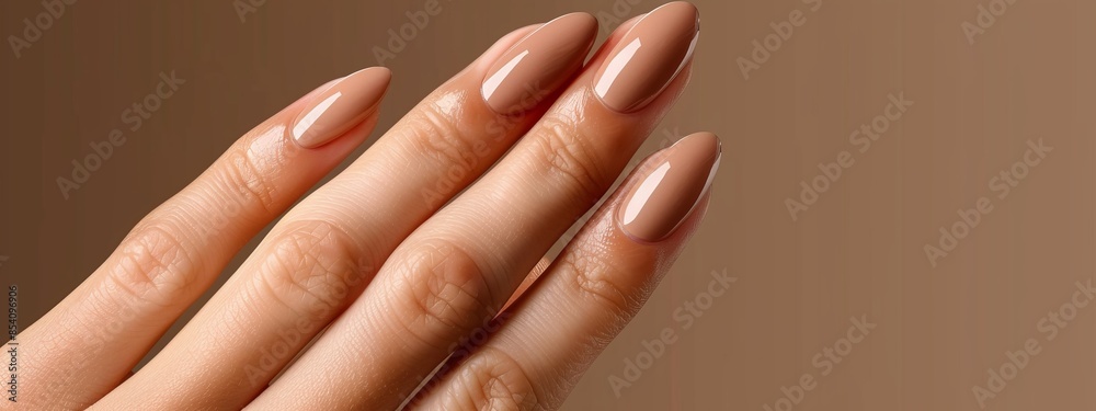 Fototapeta premium A women's hand with manicured nails against a brown backdrop ..Or, for a more descriptive version:..Close-