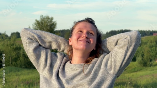 Young carefree happy woman walking at summer day at nature, enjoy good weather, deep breath fresh air and raise her arms  photo