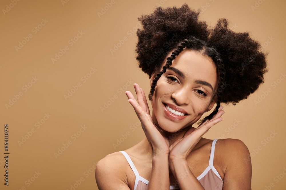 A young African American woman with a bright smile and natural beauty poses against a beige background. A young African American woman with a bright smile and natural beauty poses against a beige background.