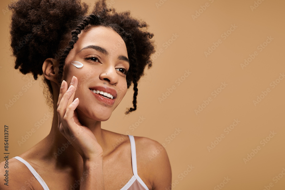 A young African American woman with a warm smile applies moisturizer to her face, showcasing the beauty of diversity. A young African American woman with a warm smile applies moisturizer to her face, showcasing the beauty of diversity.