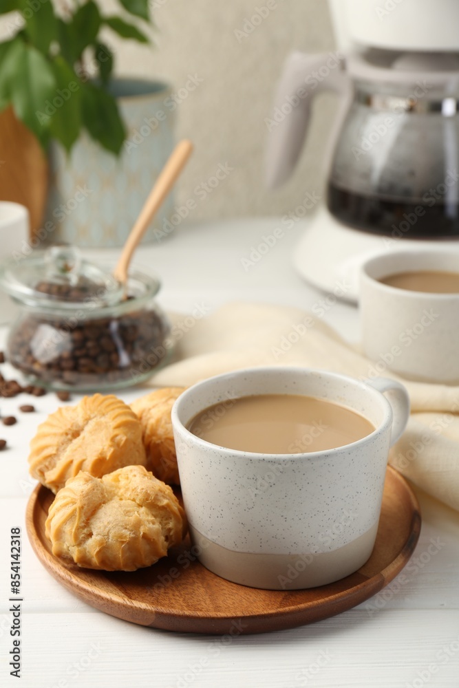 Aromatic coffee in cup and tasty profiteroles on white wooden table Aromatic coffee in cup and tasty profiteroles on white wooden table