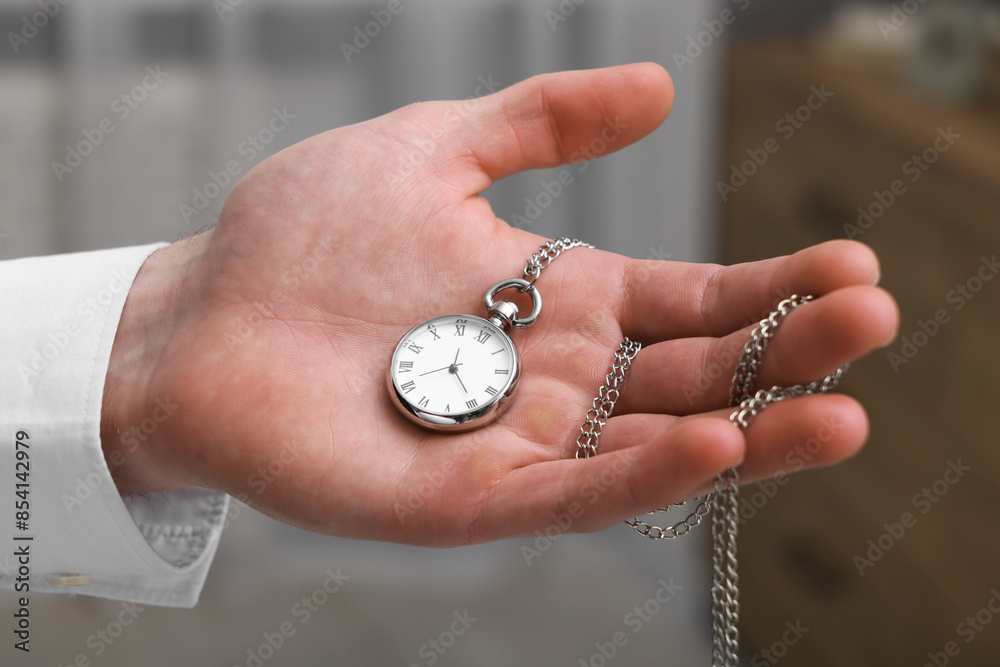 Man holding chain with elegant pocket watch on blurred background, closeup Man holding chain with elegant pocket watch on blurred background, closeup