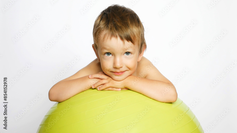 A happy cute boy lies on a big soft ball smiling A happy cute boy lies on a big soft ball smiling