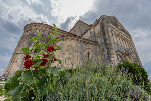 Sainte-Radegonde medieval Church, Talmont sur gironde surrounding wit beautiful dark pink hollyhocks against stormy sky photo