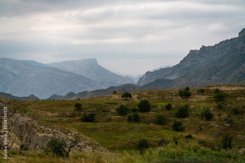 A mountain range with a cloudy sky in the background. The sky is overcast and the mountains are covered in trees. A mountain range with a cloudy sky in the background. The sky is overcast and the mountains are covered in trees.