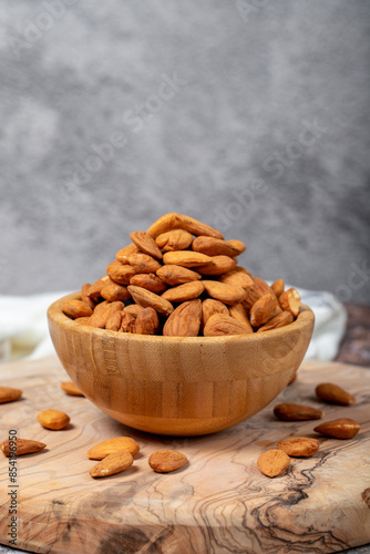 Almonds on wood background. Roasted almonds in a bowl. Close up