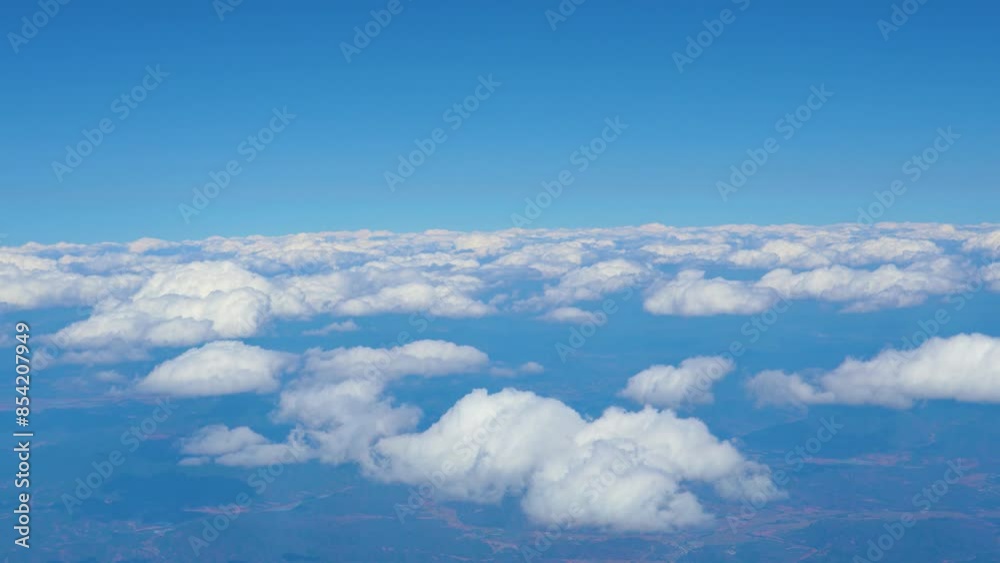 View from an airplane of flat cumulus clouds above the ground View from an airplane of flat cumulus clouds above the ground